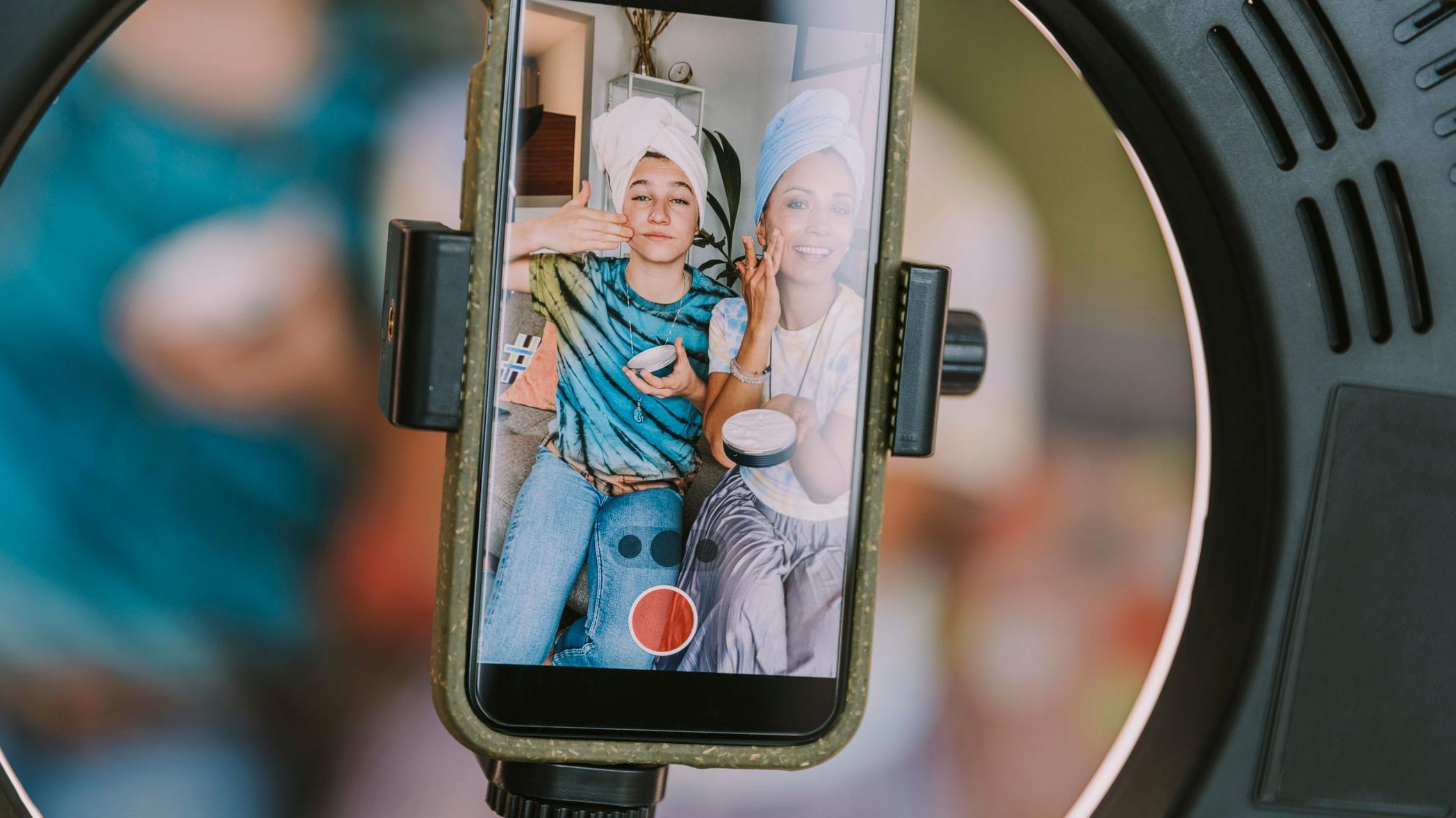 Dos jóvenes se ponen crema ante la cámara de un celular.