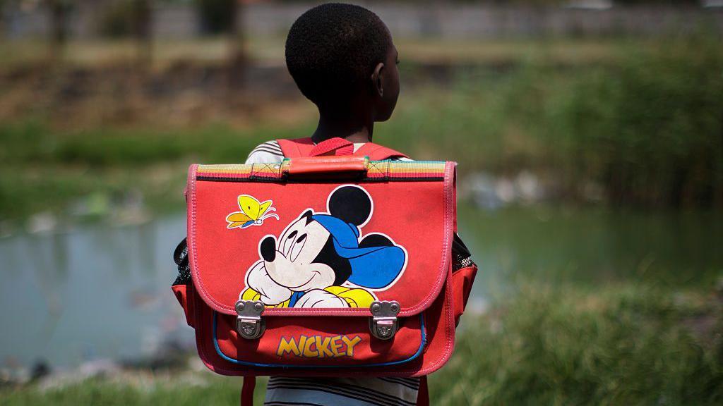 Un niño con una cartera de Mickey Mouse