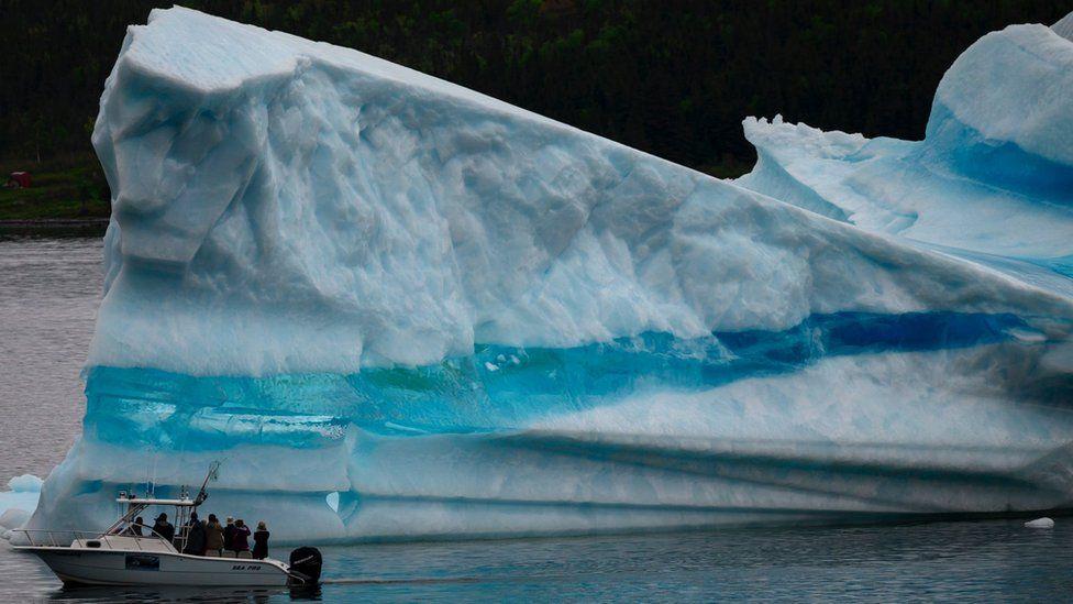 Barco ao lado de grande iceberg 