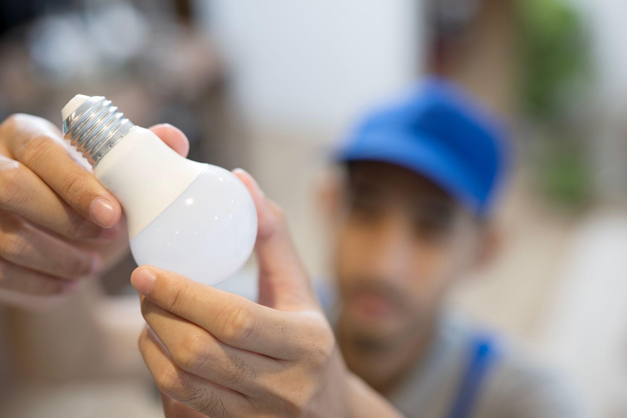 Un hombre sujeta una bombilla LED con ambas manos