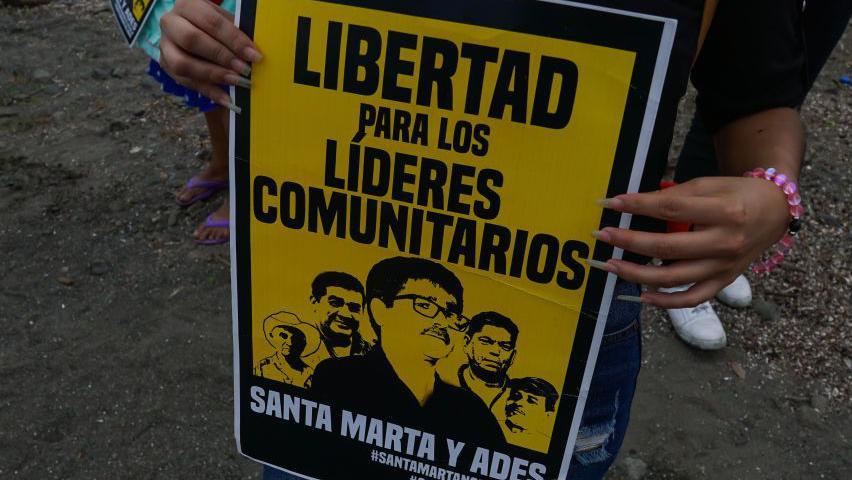 Una mujer sostiene un cartel en el río fronterizo “Ouija” durante una protesta de organizaciones ambientalistas y comunidades fronterizas entre El Salvador y Guatemala contra la minería, en el marco del Día de la Tierra, en Santa Ana, El Salvador, el 21 de abril de 2023.
