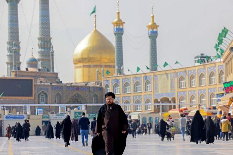 رجل دين شيعي يسير أمام ضريح فاطمة معصومة في مدينة قم الإيرانية المقدسة جنوب طهران