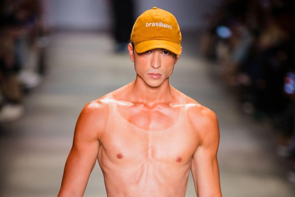 Modelo sem camisa desfila com boné na semana de moda de São Paulo