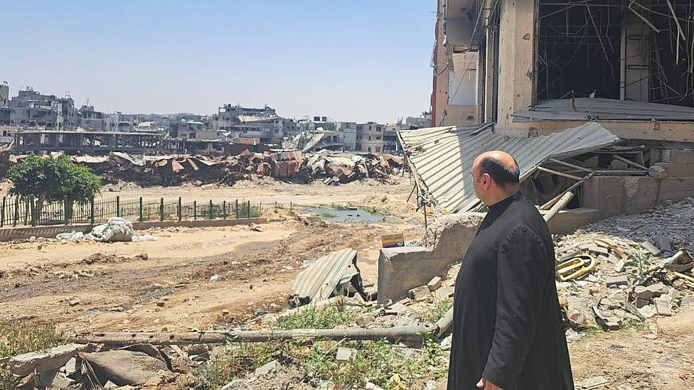 Padre Gabriel viendo edificios destruidos por bombardeos isrealíes