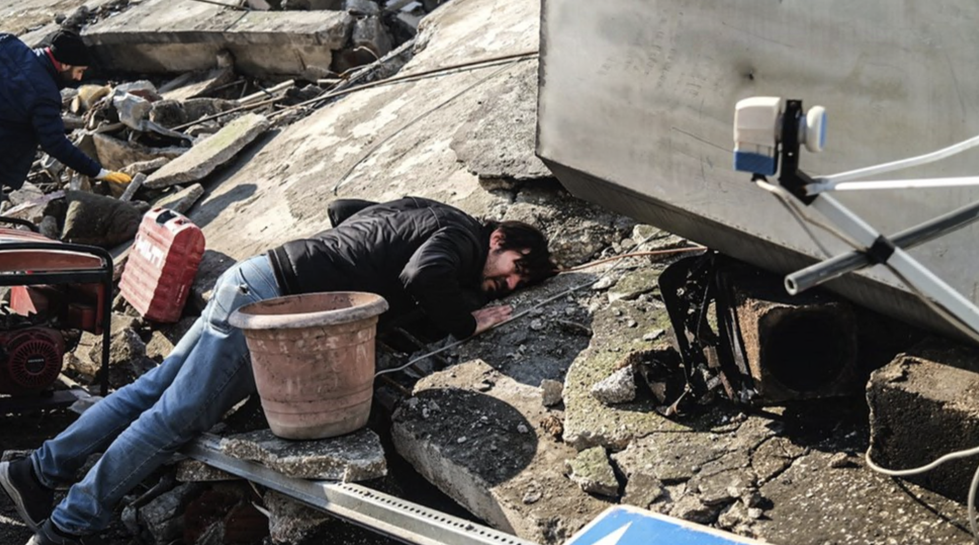Um homem coloca o ouvido nos escombros tentando ouvir sobreviventes presos na província de Hatay, na Turquia