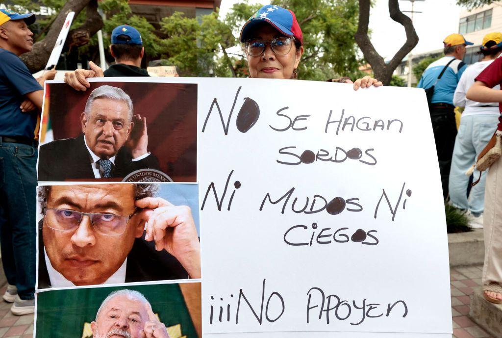 Opositora protestando en Caracas con cartel de los presidentes de México, Colombia y Brasil 