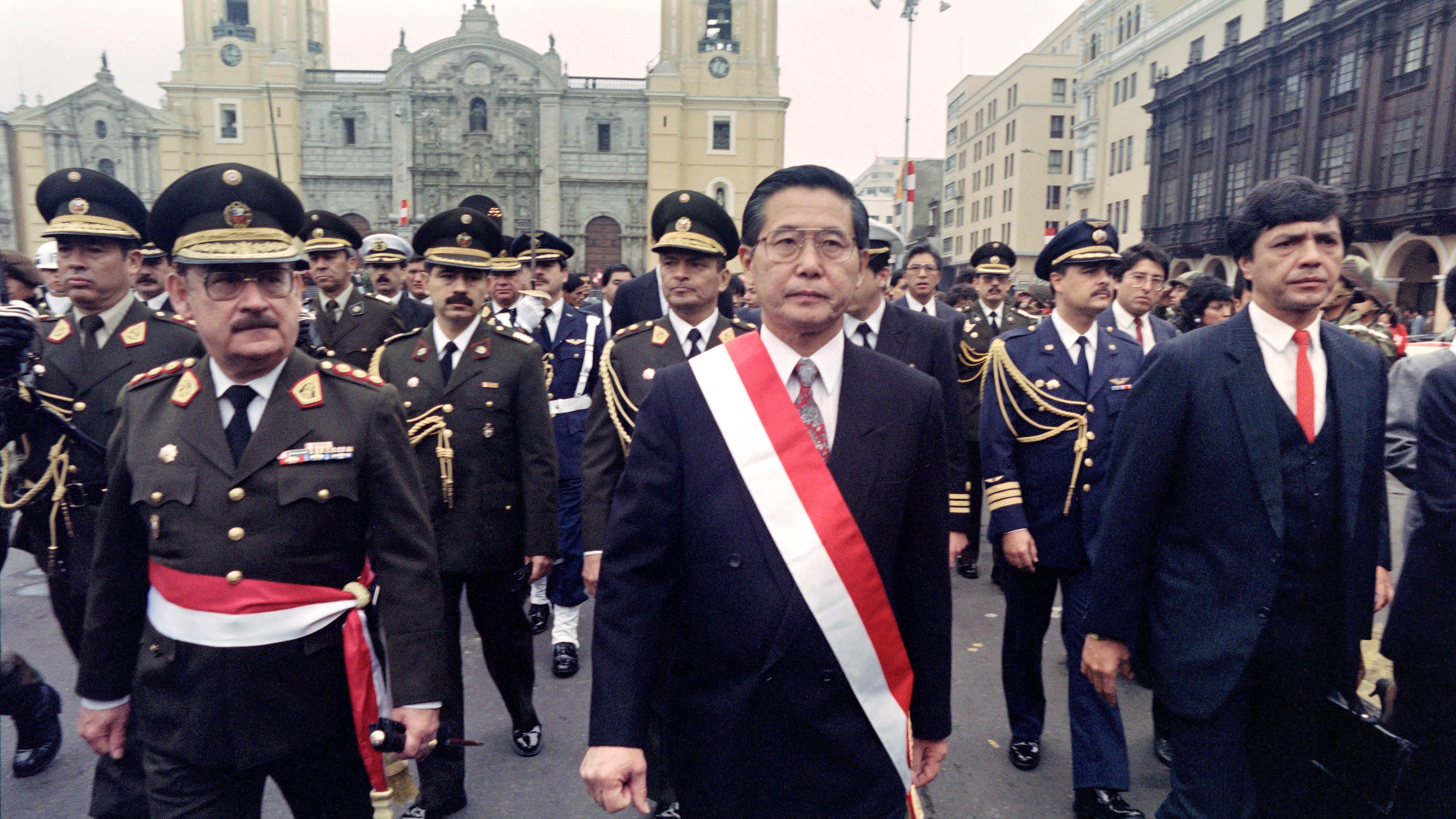 Alberto Fujimori camina por el centro de Lima con la banda presidencial de Perú en el torso y rodeado de militares.