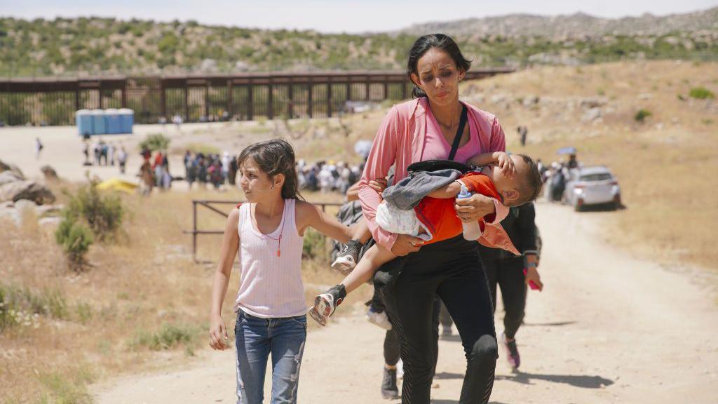 Una mujer camina con dos niños en la frontera sur de EE.UU. 