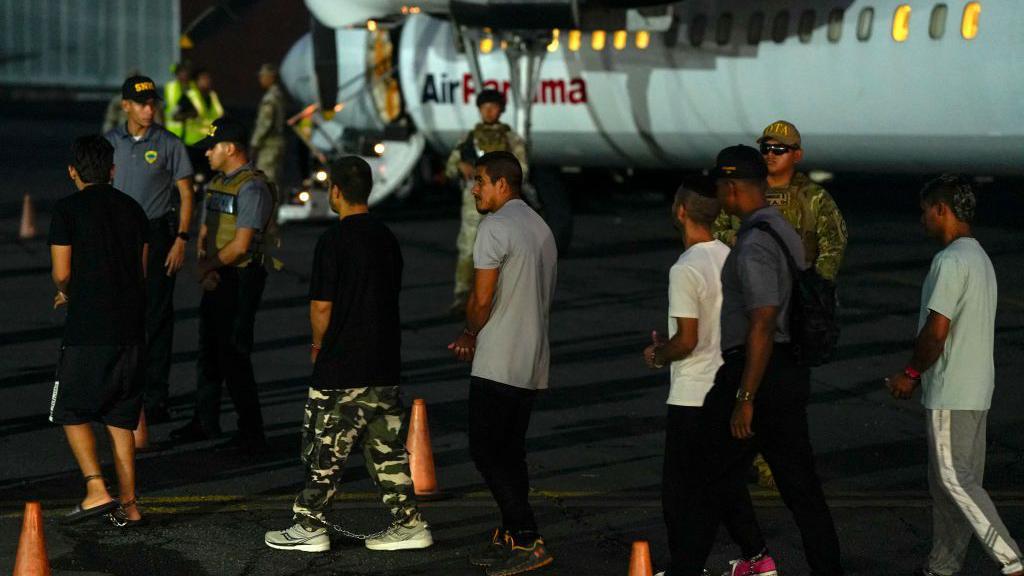 Migrantes colombianos, con las manos y los pies esposados, hacen fila para subir a un avión en el aeropuerto Albrook Gelabert de la ciudad de Panamá el 20 de agosto de 2024, durante su deportación. 