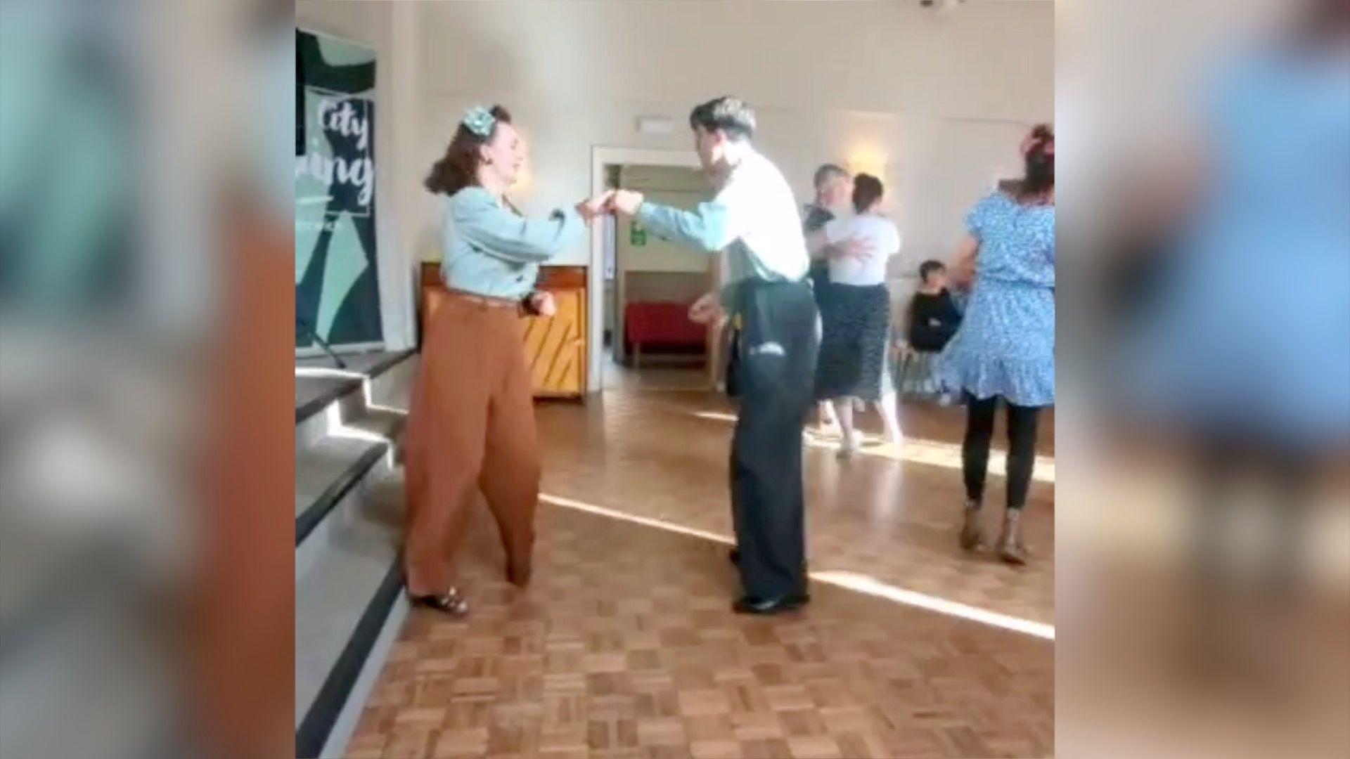 Liberty e Greg dançando com roupas tradicionais dos anos 40