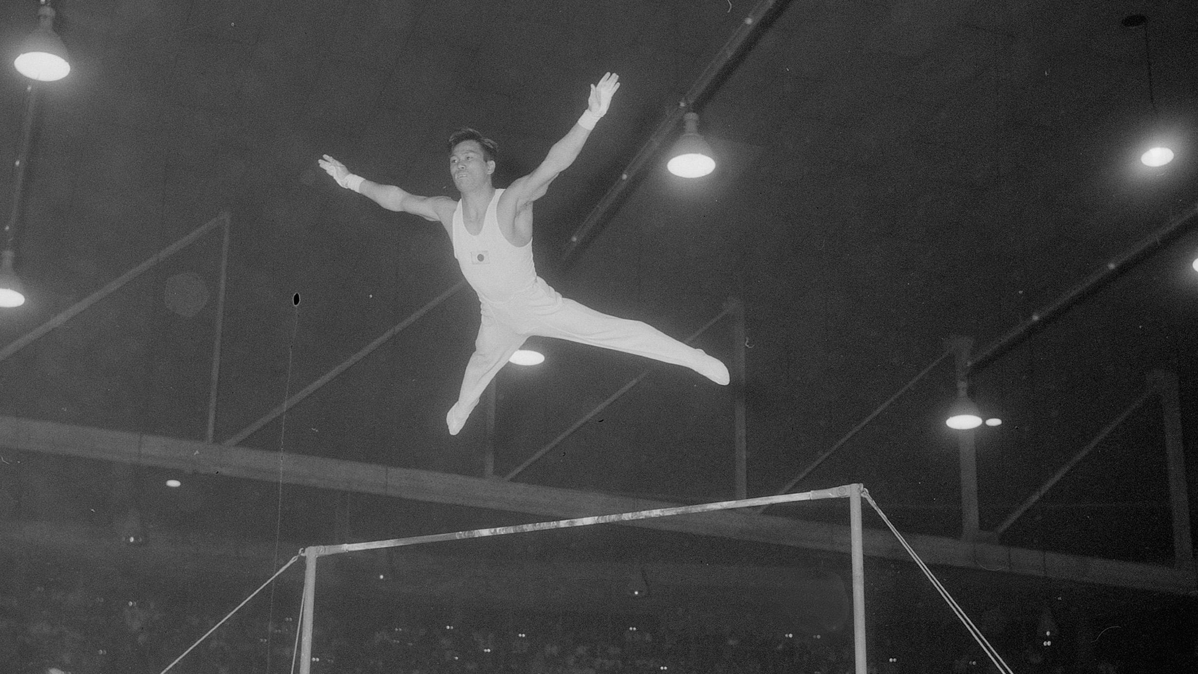 Takashi Ono saltando en un ejercicio de barra fija