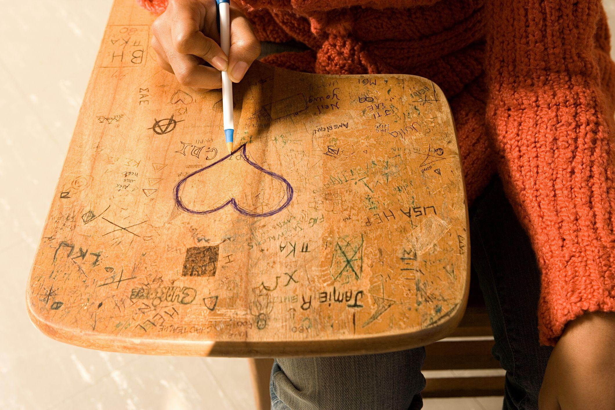 Menina desenhando coração na mesa