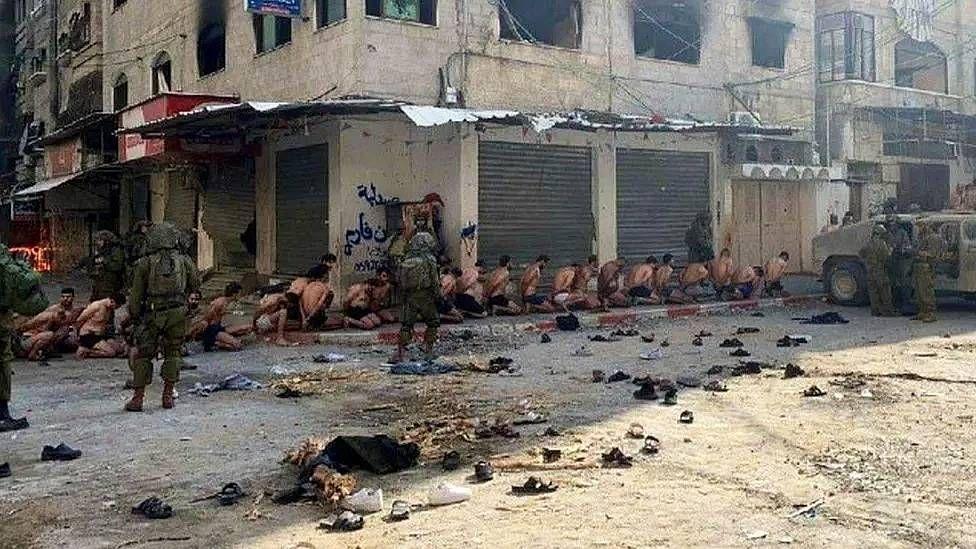 Hombres en calzoncillos arrodillados custodiados por soldados israelíes en Gaza