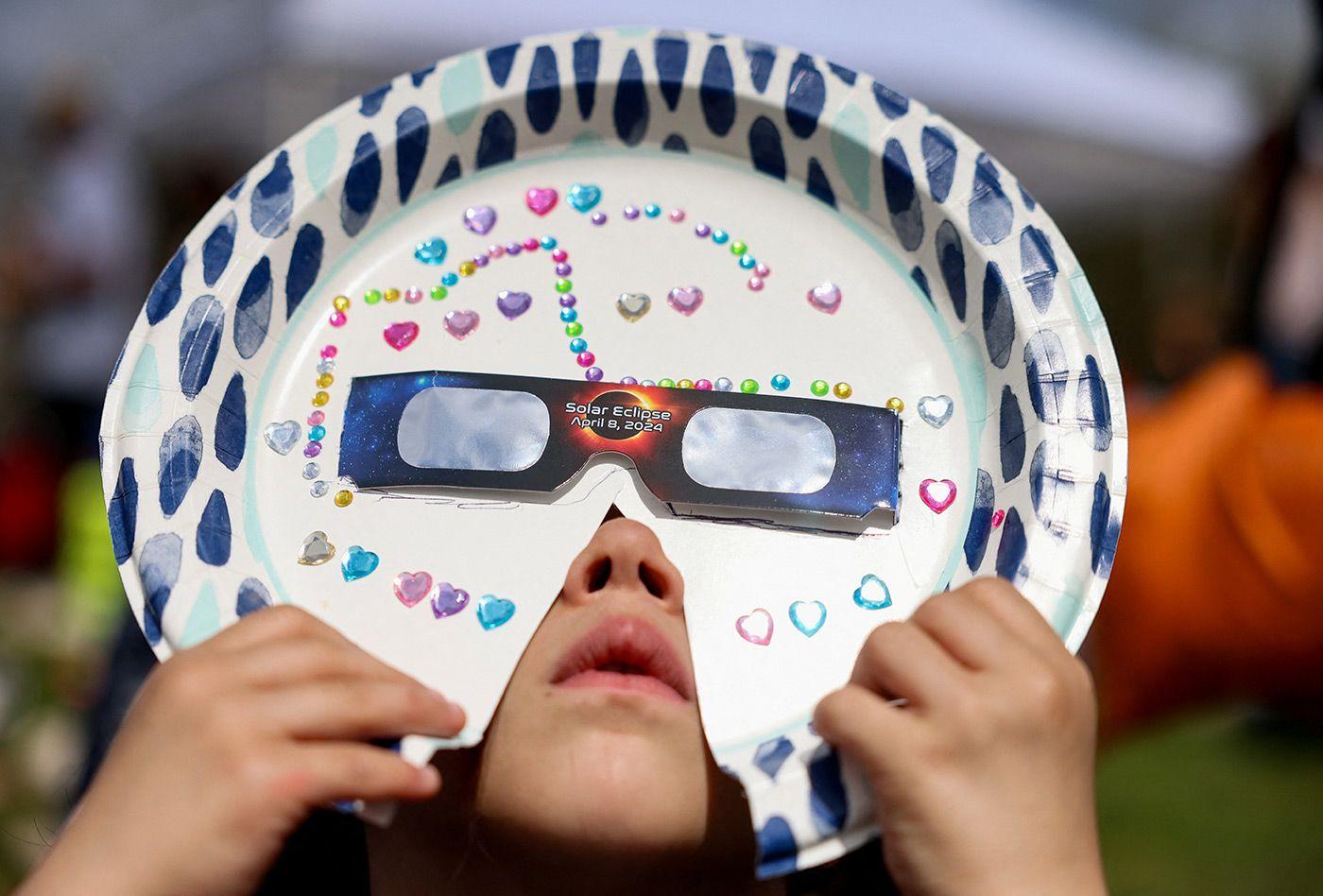 Criança observando o eclipse com óculos de proteção customizado, feito de prato de papelão