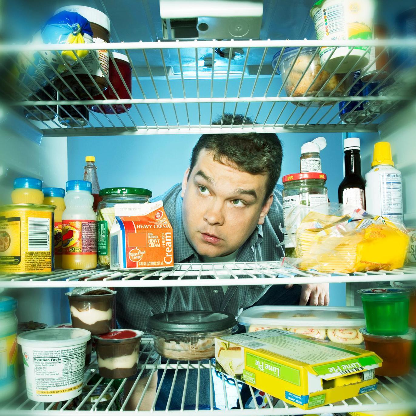Un hombre mira dentro de un refrigerador