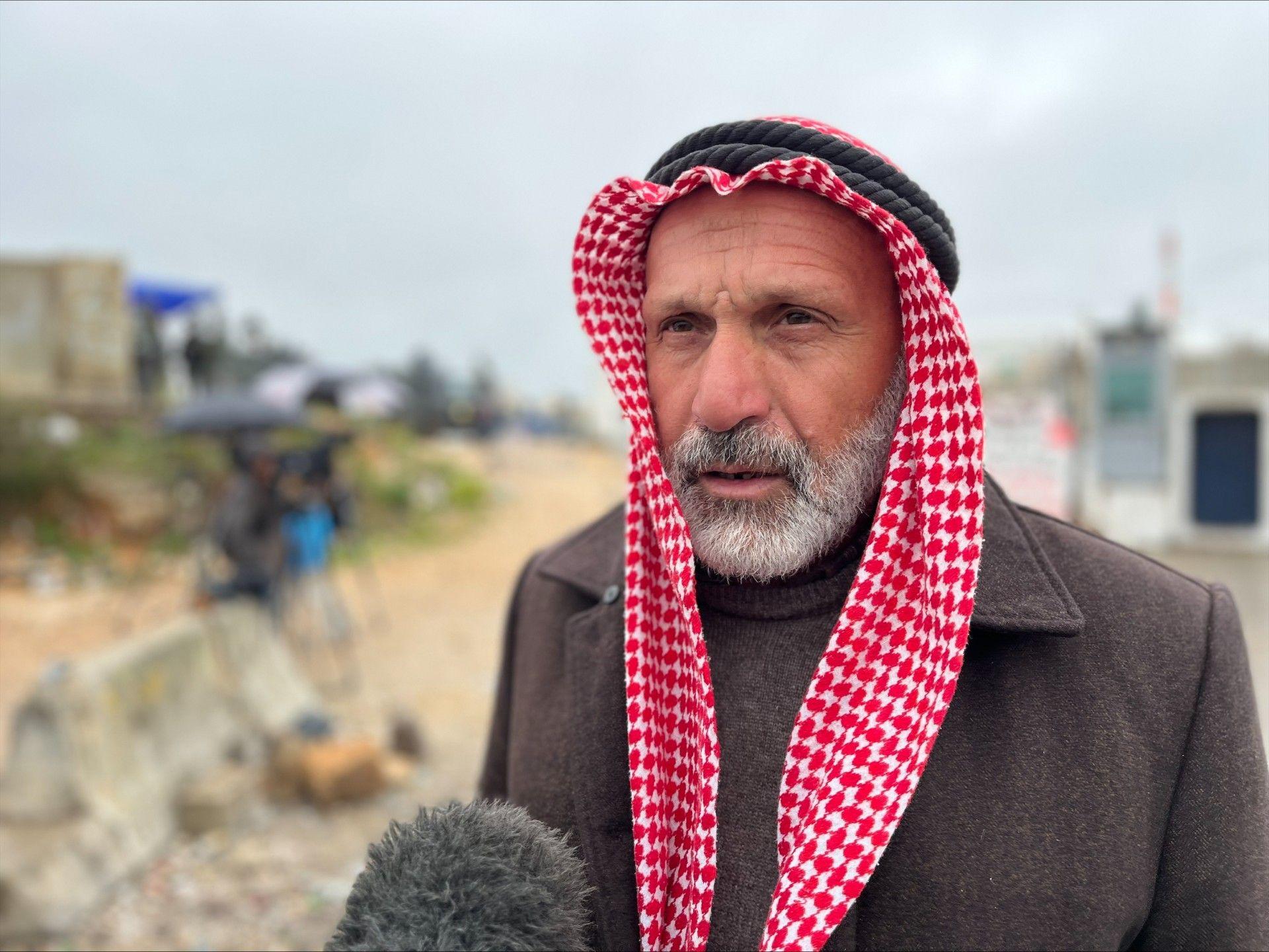 خالد رواد بشرته بيضاء ولحيته شائبة. يرتدي شماغاً بلون أحمر وأبيض يغطي رأسه، ومعطفاً شتوياً بنياً وتحته قميص شتوي بني