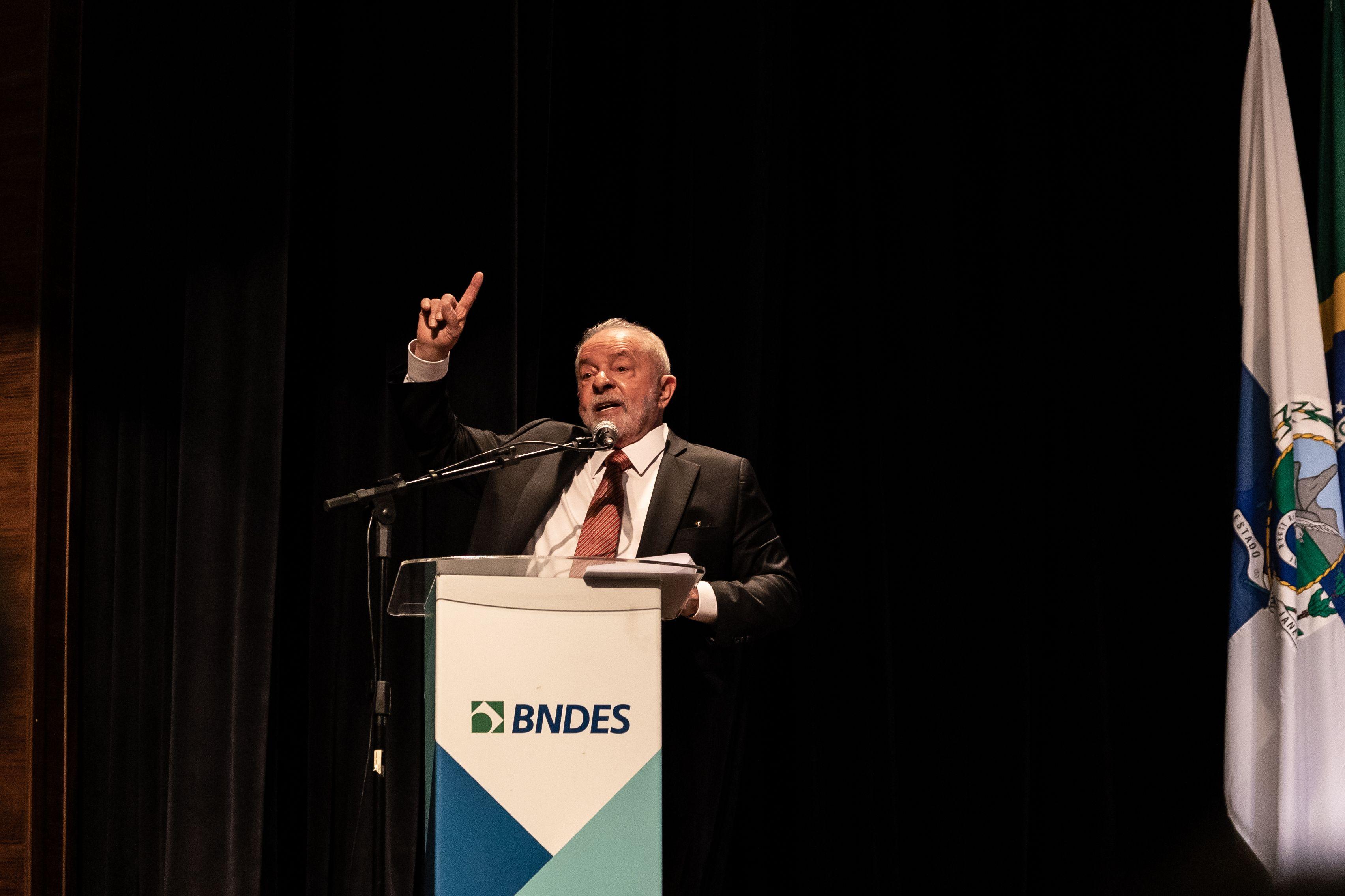 Lula habla detrás de un atril con las siglas del banco de desarrollo brasileño BNDES 
