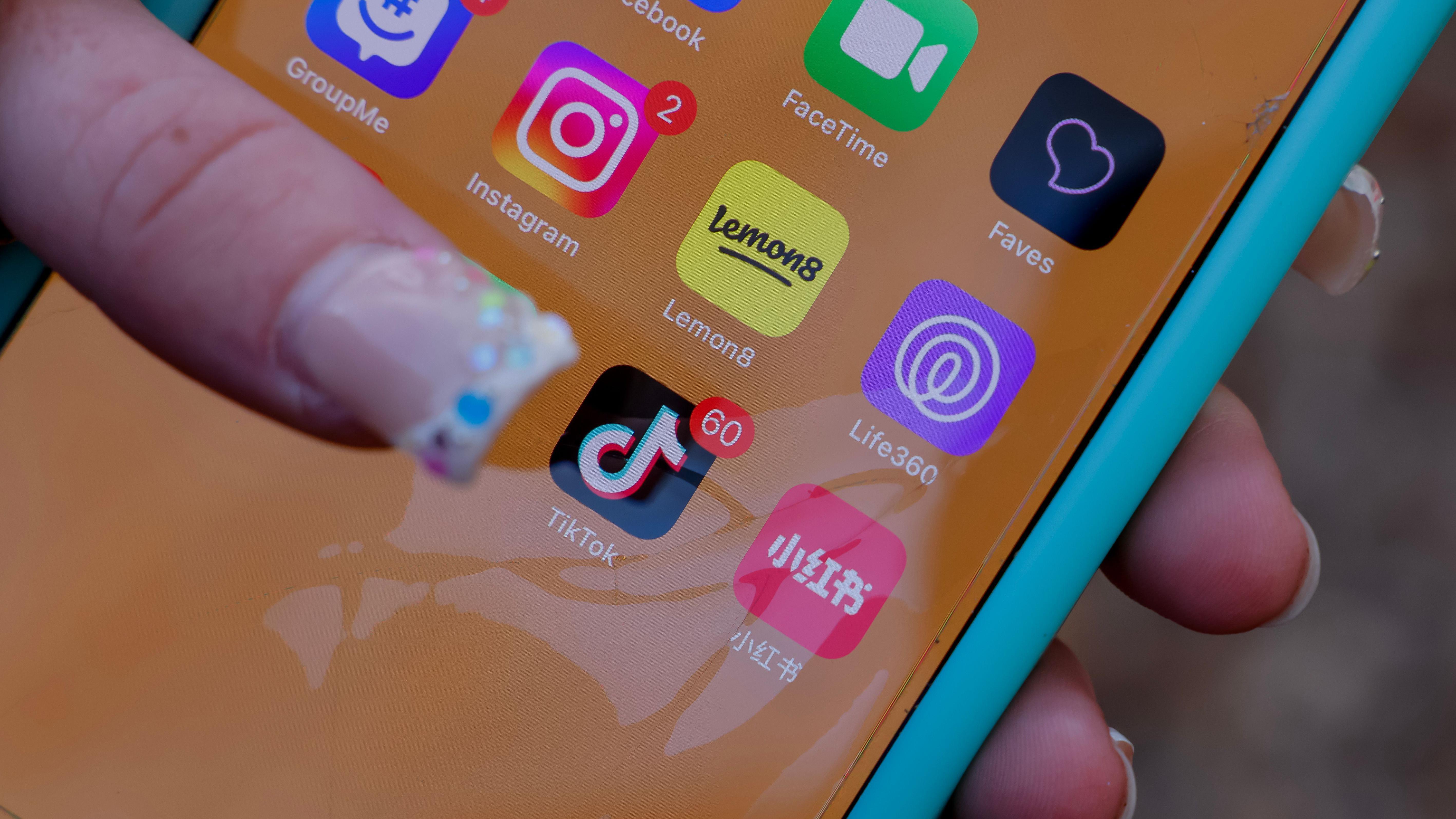 Pantalla de móvil con un dedo sobre la aplicación de TikTok entre otras