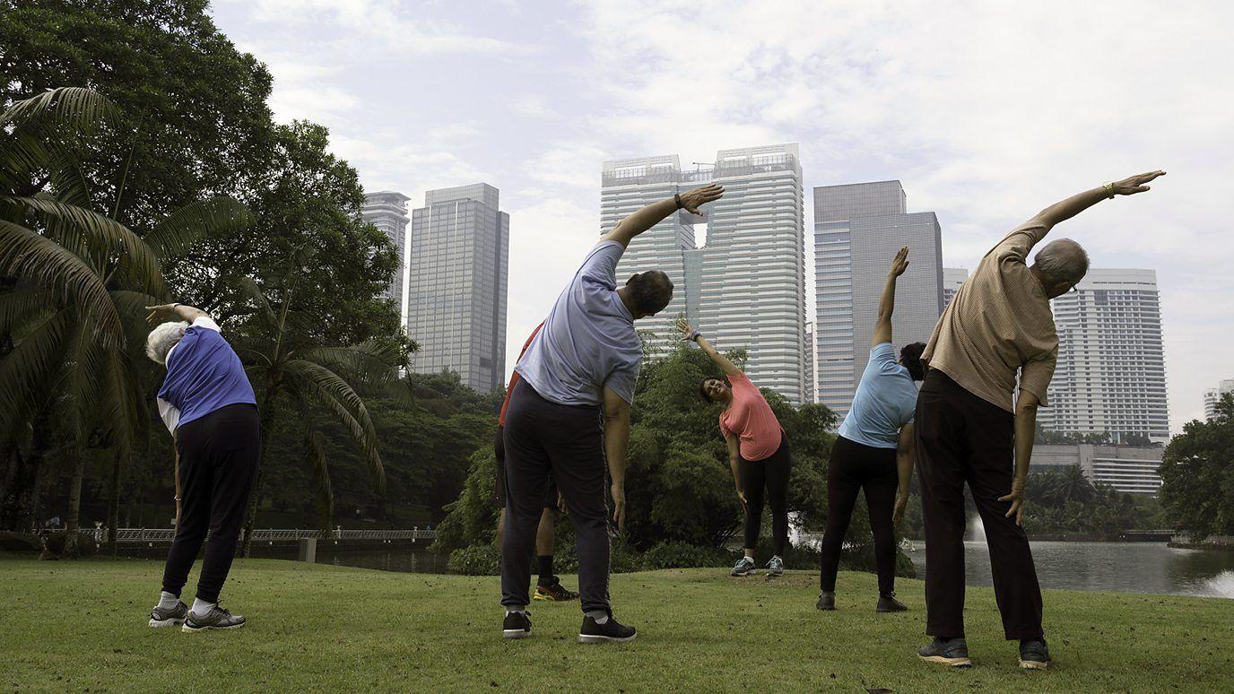 Grupo de pessoas praticando alongamento em parque público de Cingapura 