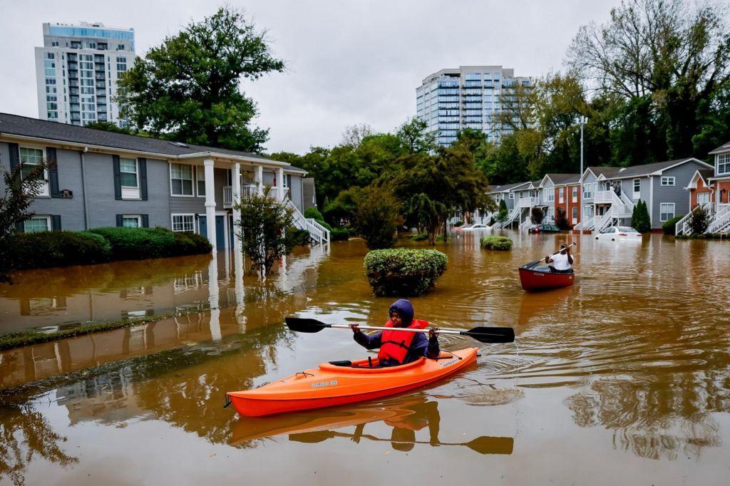 Two people kayak across a residential street 