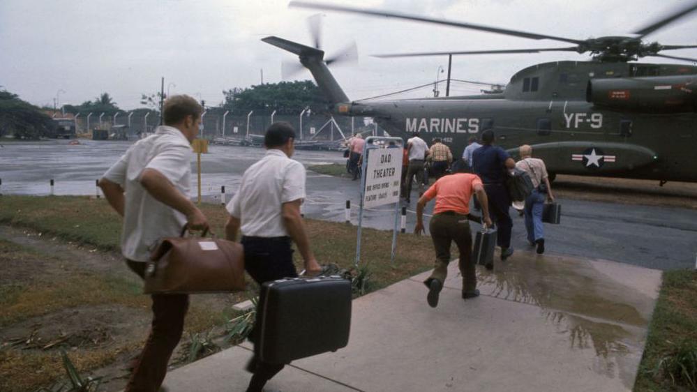 Estadounidenses que huyen abordan un helicóptero de la Marina de los EE. UU. en la base aérea de Tan Son Nhut en Saigón, abril de 1975.