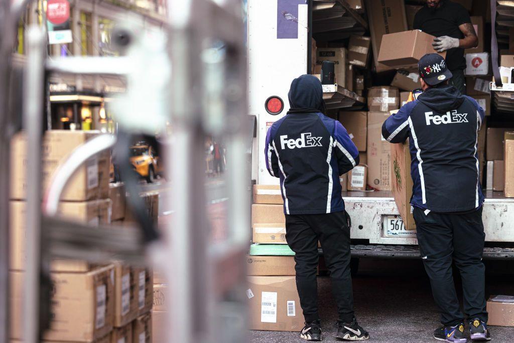 Dos trabajadores de FedEx descargando paquetes de un camión