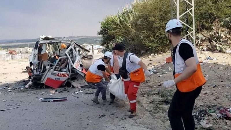 Four aid workers working by a damaged ambulance