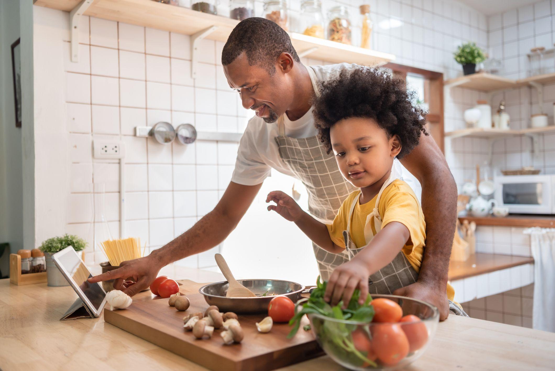 Pai preparando refeição com filha na cozinha de casa