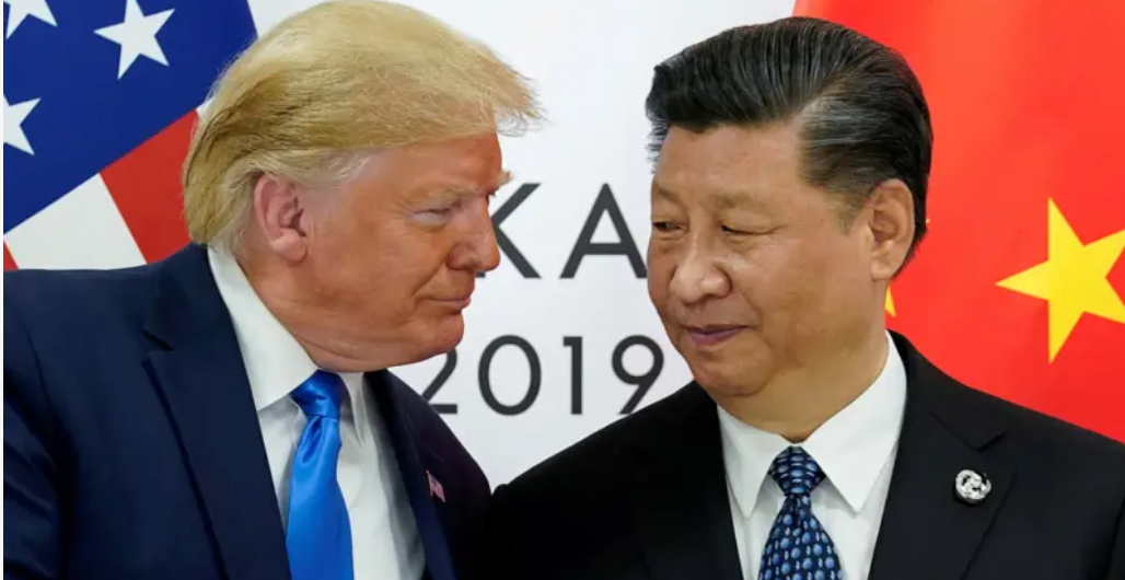 Donald Trump e Xi Jinping em 2019, usando terno e gravata, com as bandeiras dos respectivos países atrás