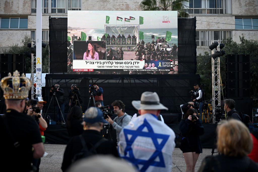 Pessoas em uma praa em Tel Aviv assistindo  libertao dos refns em uma tela gigante.