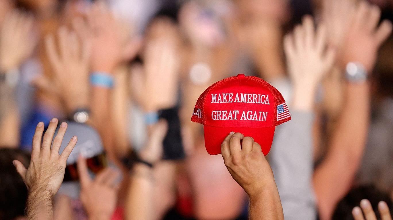 Mão ergue boné com slogan Make American Great Again bordado