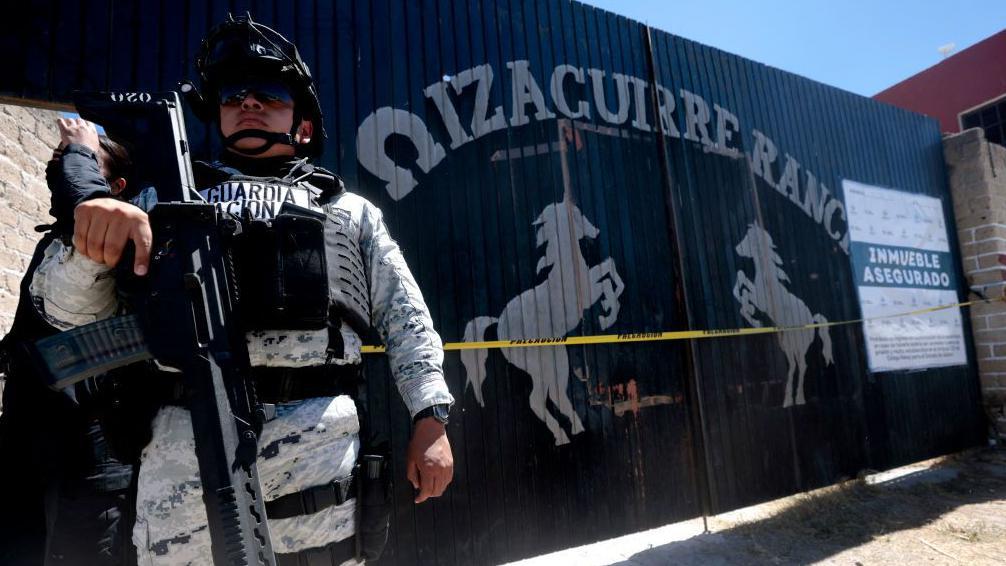 Un miembro armado de la Guardia Nacional de México vigila la entrada del Rancho Izaguirre