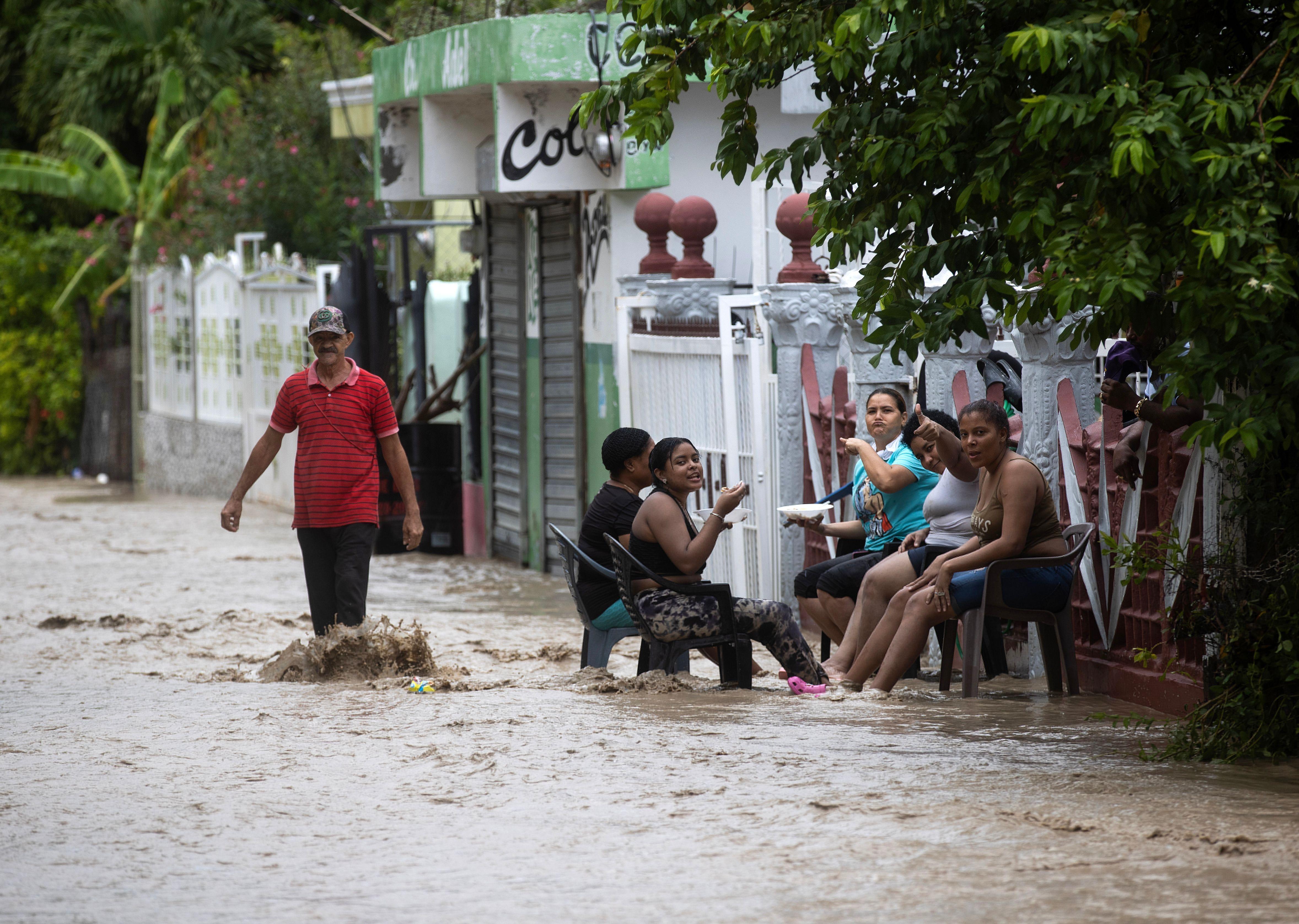 ​La gente se sienta en una calle inundada como resultado de las fuertes lluvias.