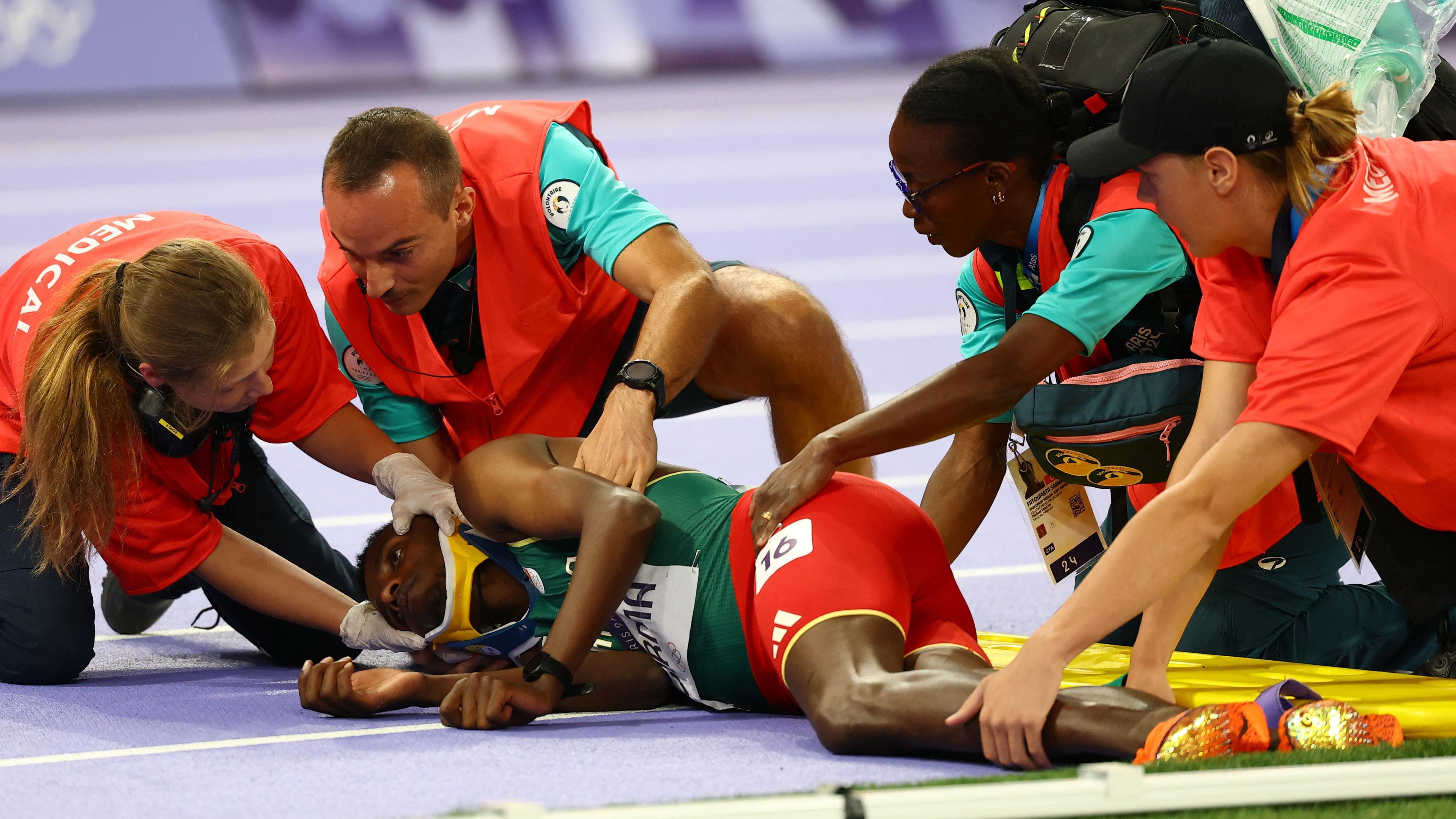 Lamecha Girma es asistido por personal médico en la pista del Stade de France.