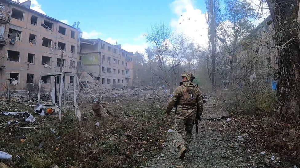 Soldado caminando entre edificios destruidos por bombardeos