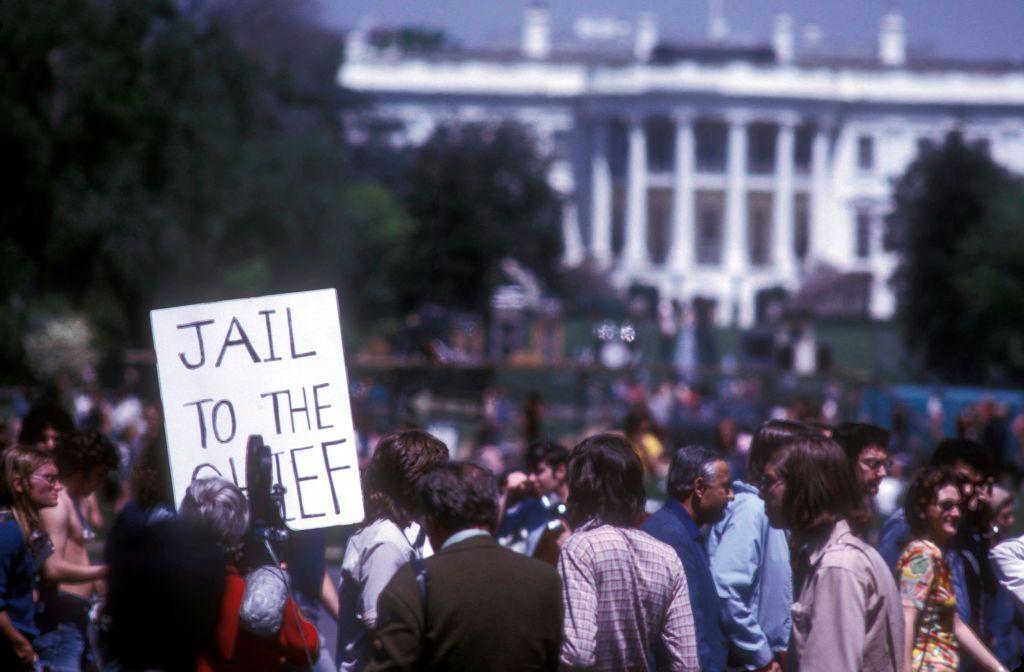 Personas protestando frente a la Casa Blanca. Se ve un cartel que dice: "Jail to the chief" ("Cárcel para el jefe")