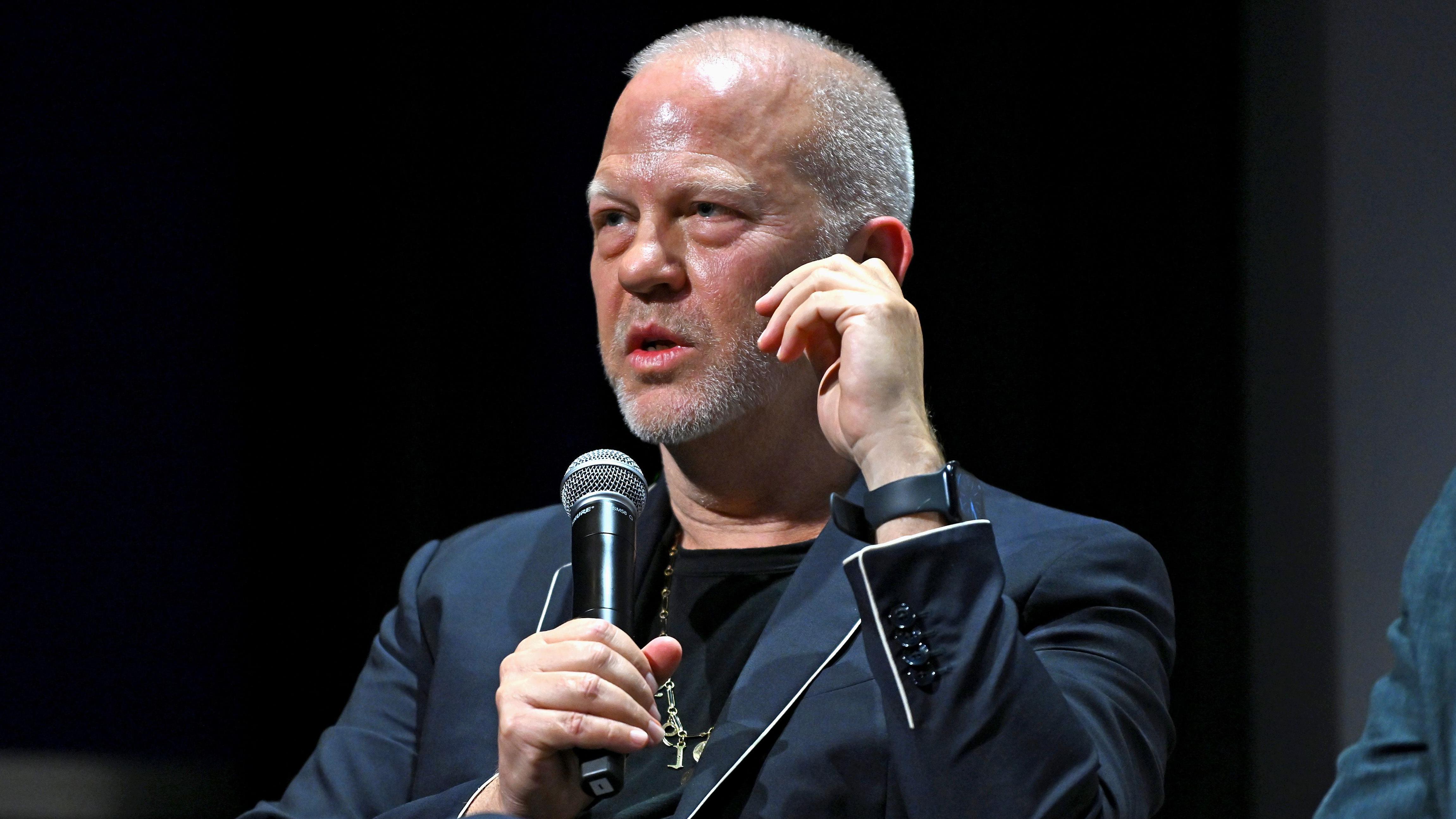 O diretor e roteirista Ryan Murphy, vestindo um terno azul marinho e segurando um microfone, em um evento em Nova York no início deste mês