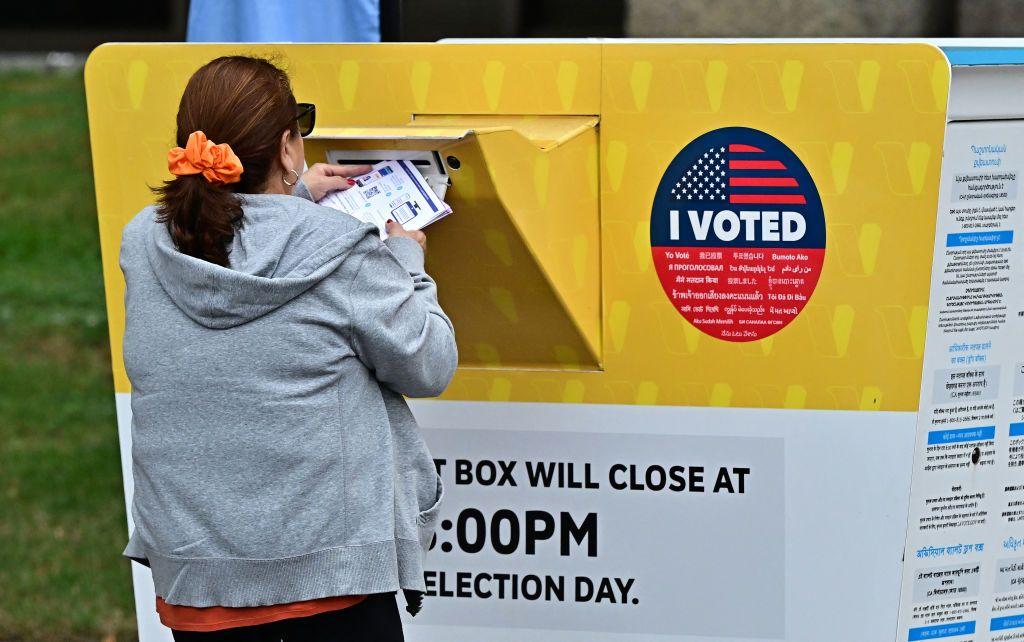 Mulher entrega uma cédula de votação no Cartório Eleitoral do Condado de Los Angeles, Califórnia. 