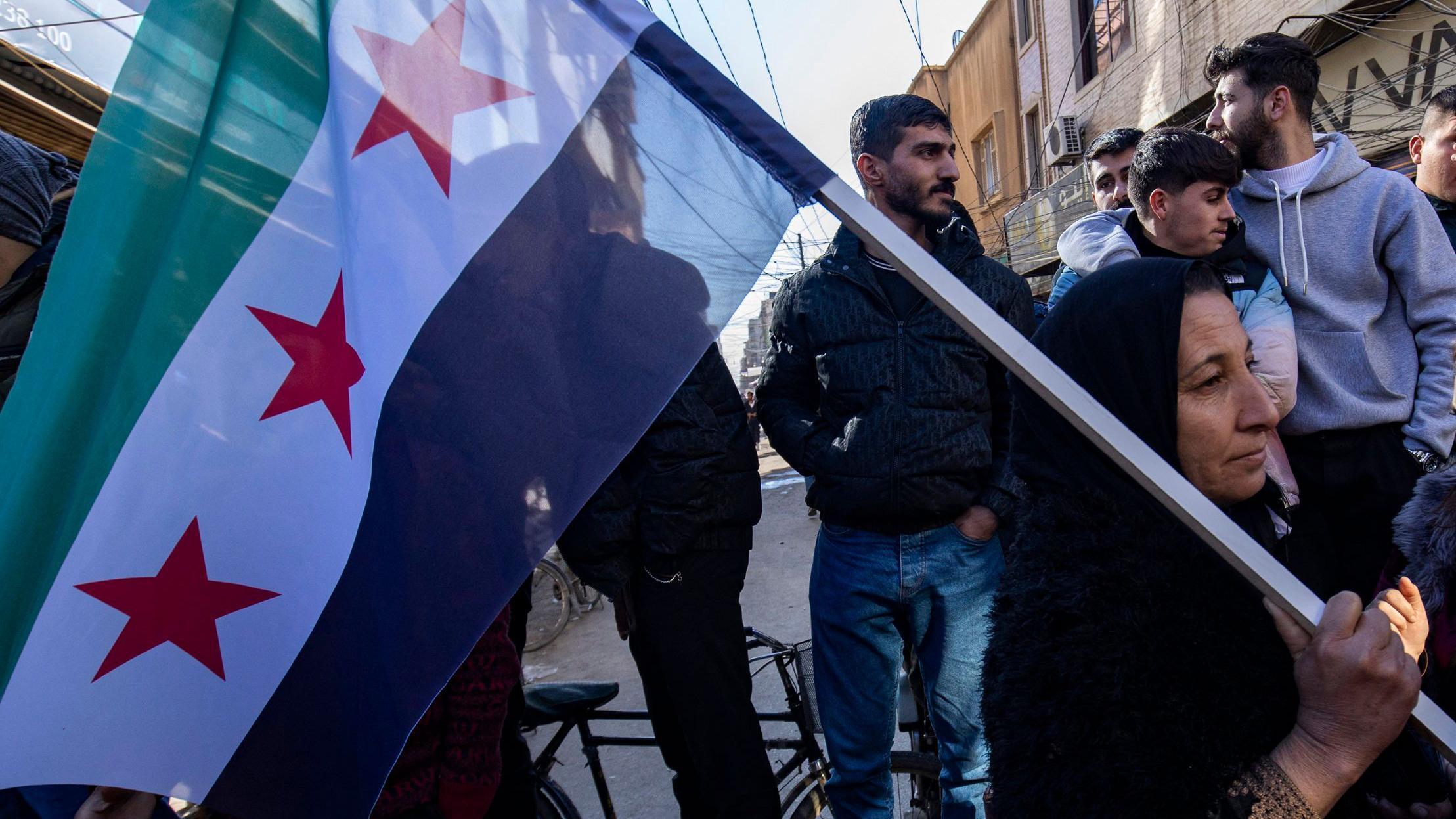 يحمل أحد الأكراد السوريين علم الاستقلال خلال مظاهرة لدعم قوات سوريا الديمقراطية التي يقودها الأكراد والتي تدعمها الولايات المتحدة في مدينة القامشلي شمال شرق البلاد