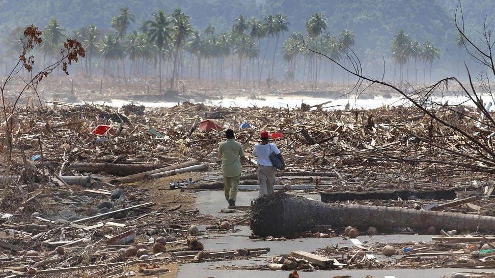 Dos hombre caminan entre la devastación causada por el tsunami de Indonesia en 2004.