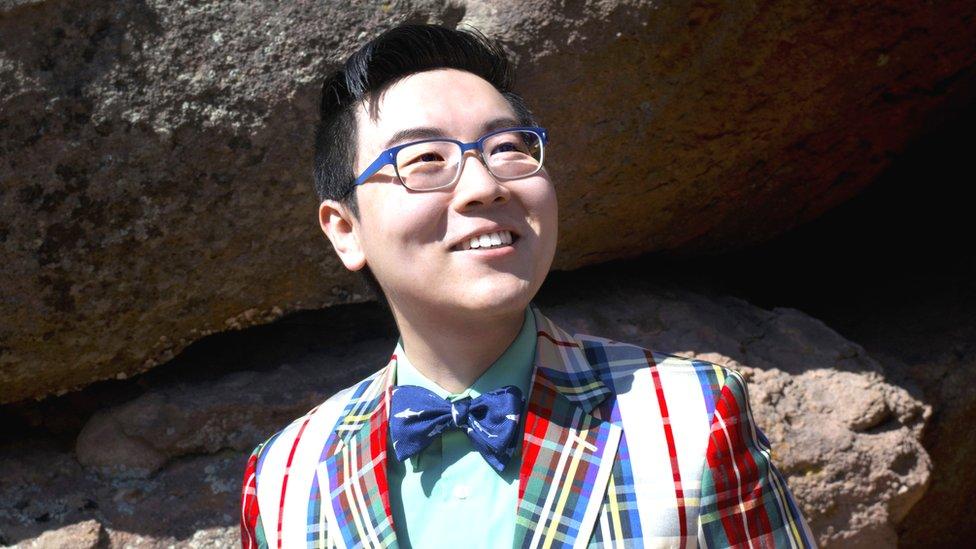 Zhenghua Yang sorrindo em ambiente natural, com pedras