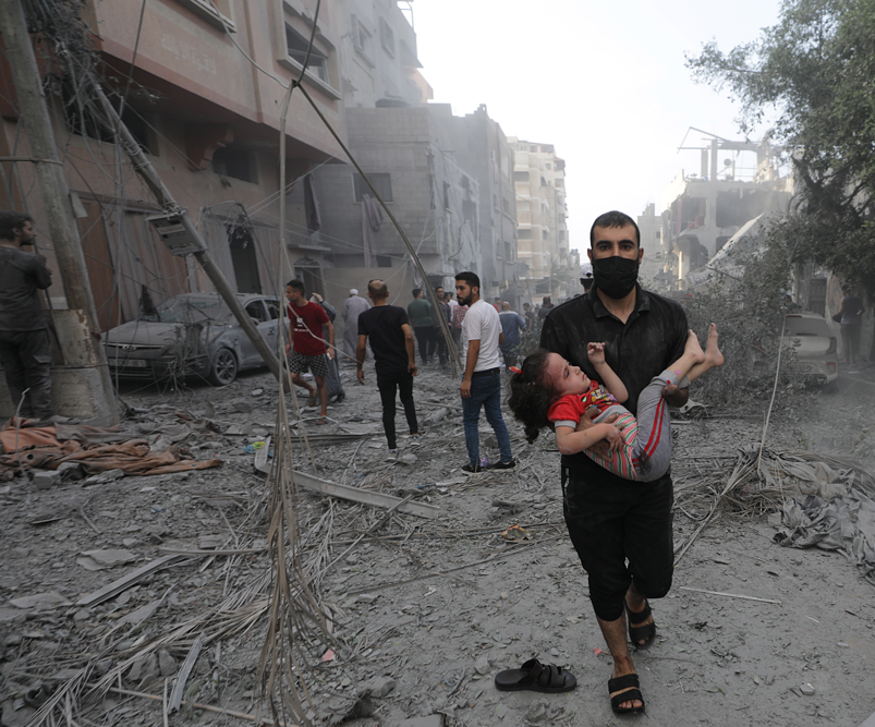 رجل يحمل طفلة مصابة جرّاء القصف الإسرائيلي على قطاع غزة.