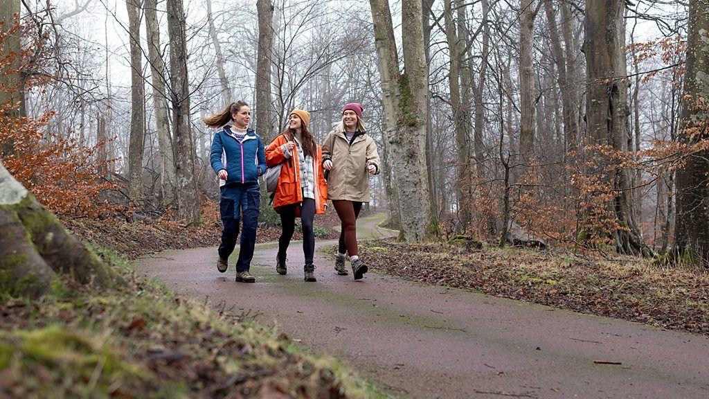 Três mulheres caminhando juntas no parque