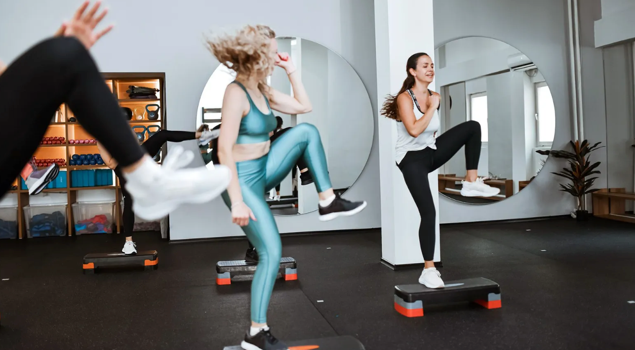 Grupo se exercita em academia, com espelhos ao fundo