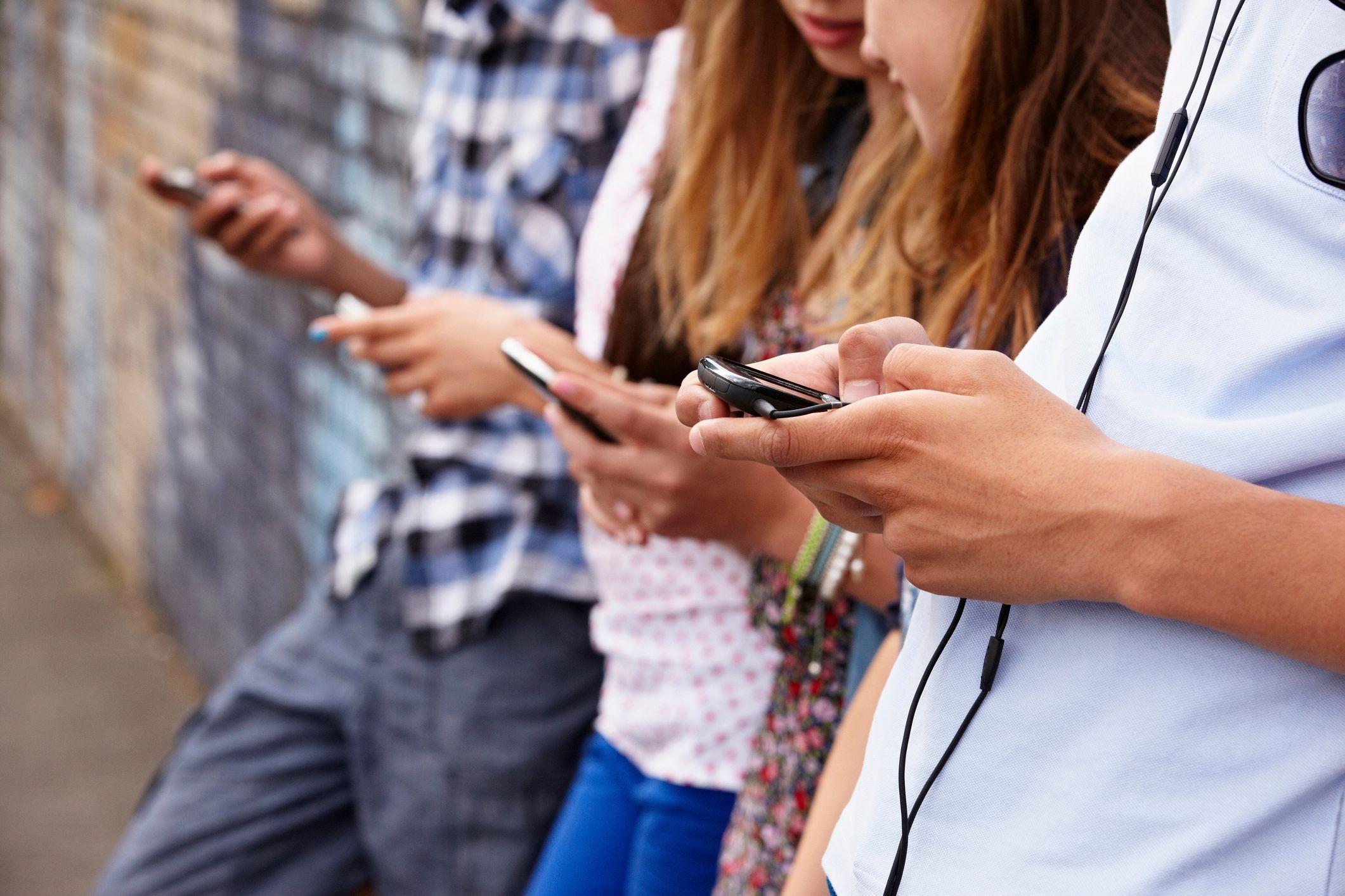 Adolescentes miran sus teléfonos