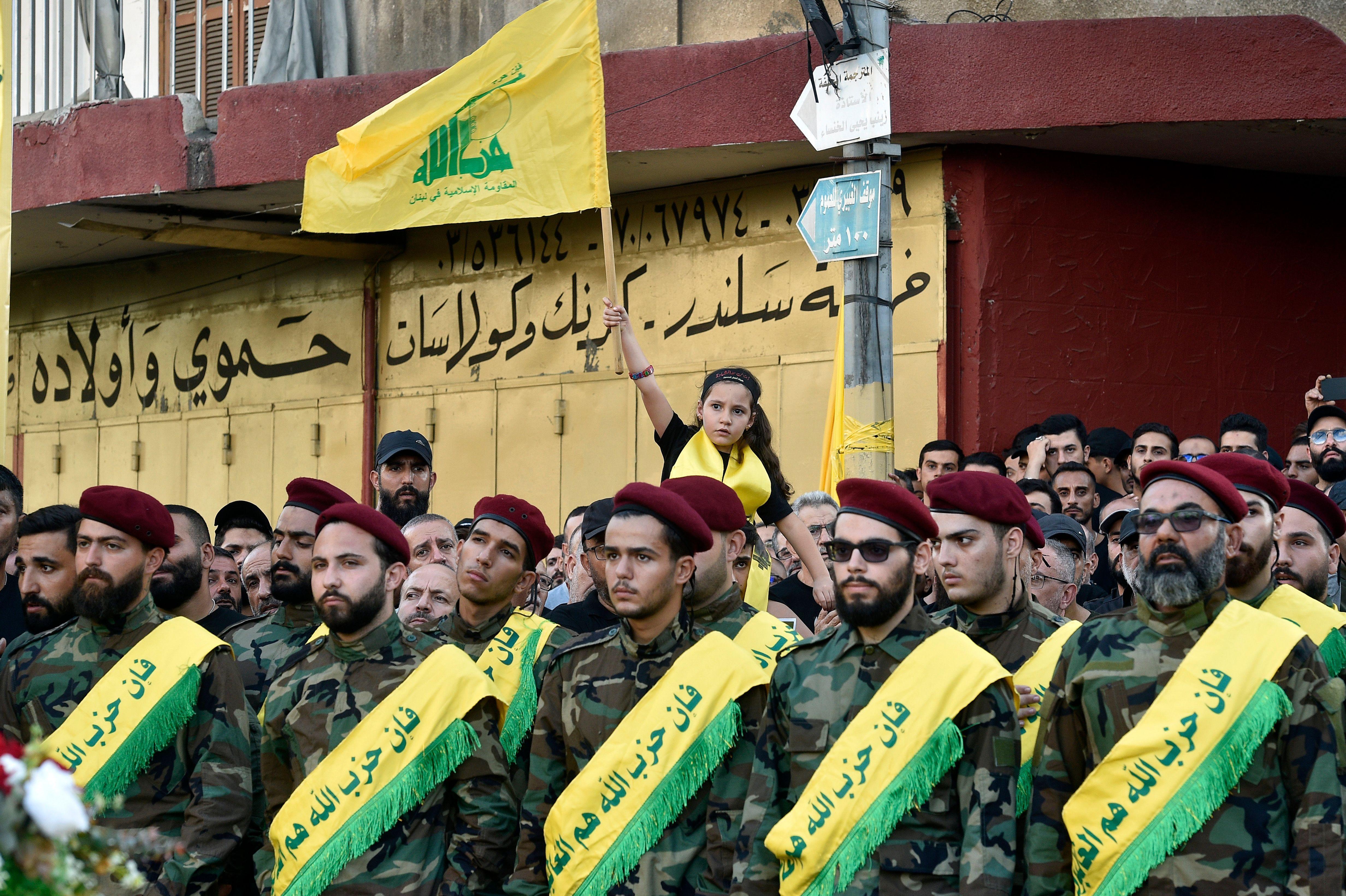 Una niña agita una bandera mientras milicianos de Hezbolá despiden a uno de los dirigentes muertos. 