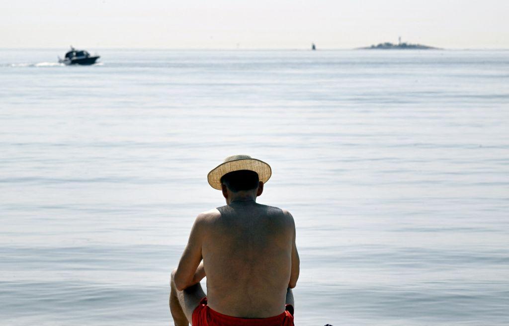رجل يأخذ حمام شمس على البحر في هلسنكي، فنلندا، في يوم صيفي حار في 15 يونيو/ حزيران 2023. 