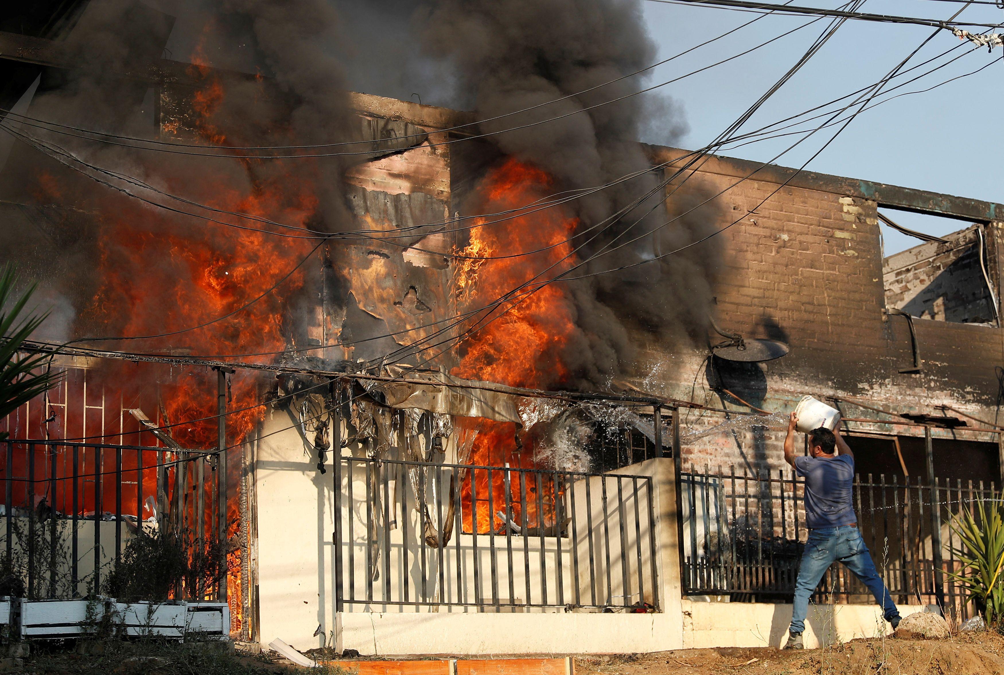 Un hombre intenta apagar un incendio en una casa.