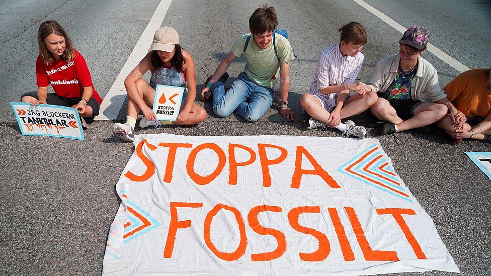 Thunberg y otros jóvenes bloqueando una vía de acceso a una instalación petrolera
