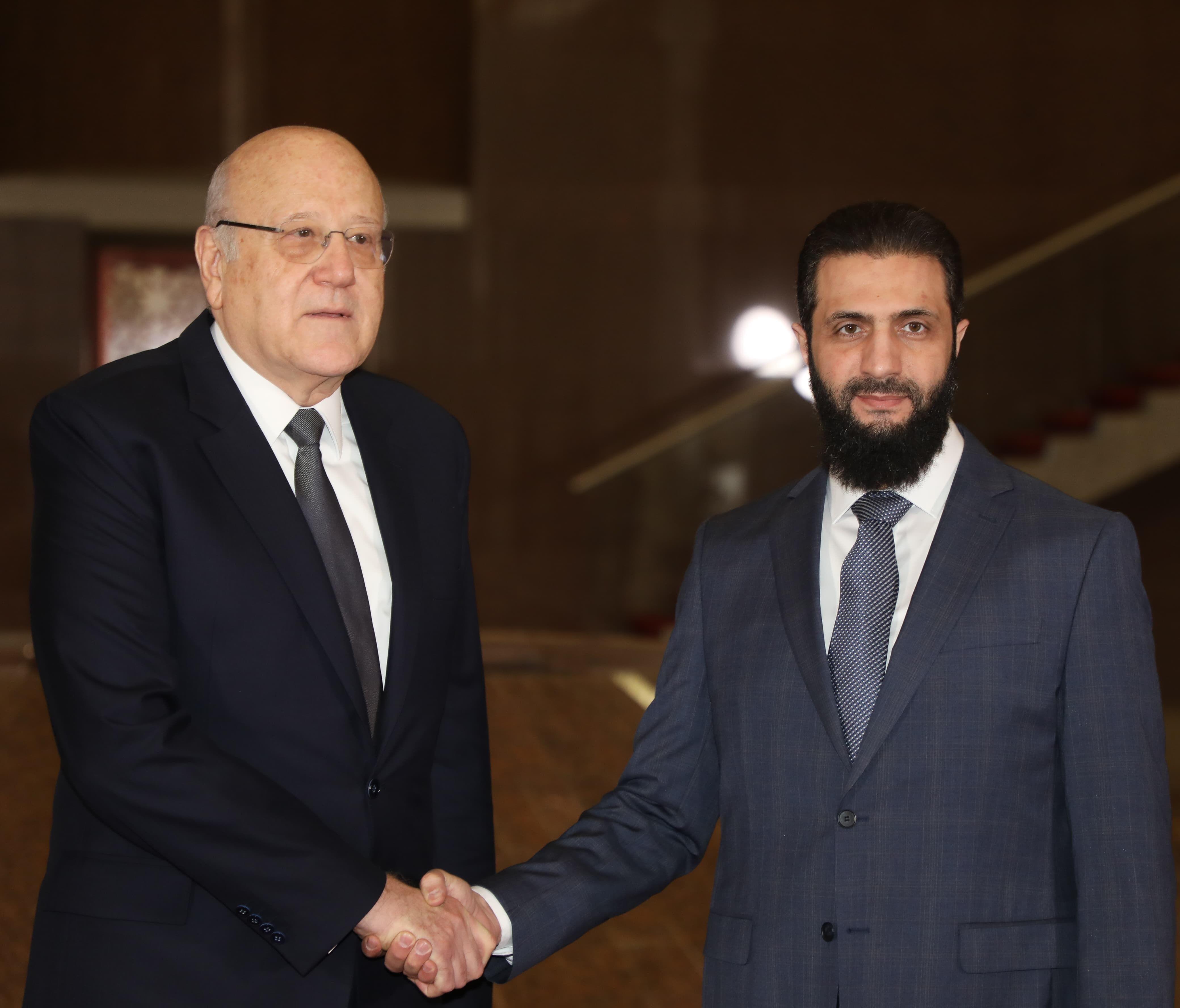 رئيس الوزراء اللبناني نجيب ميقاتي (يسار) وهو يصافح رئيس الإدارة السورية الجديدة أحمد الشرع (يمين)، المعروف أيضًا باسم أبو محمد الجولاني، خلال لقائهما في دمشق، سوريا، 11 يناير/كانون الثاني 2025.